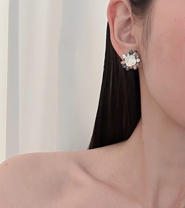 A woman wearing a pair of E2114 (Crystalize & Multi Colors) earrings with a flower on them.