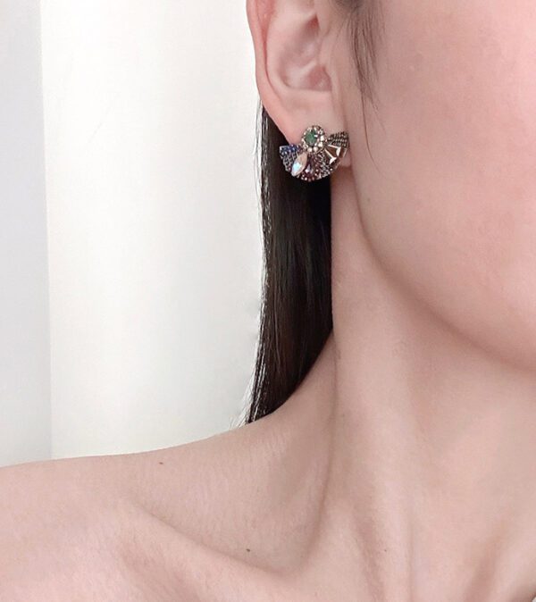 A woman wearing a pair of E2112 earrings with crystals on them.