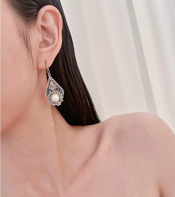 A woman wearing a pair of earrings E2105 with crystals.