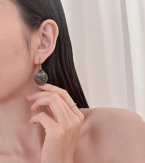 A woman with long hair wearing E2074 earrings.