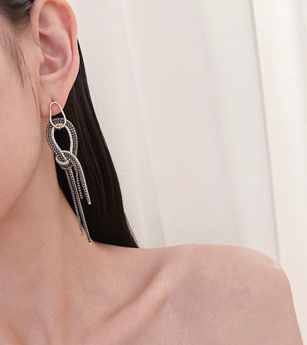 A woman wearing a pair of E2028 earrings with tassels.