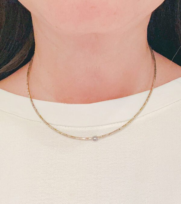 A woman wearing a NK5115 (Gold) necklace with a diamond on it.