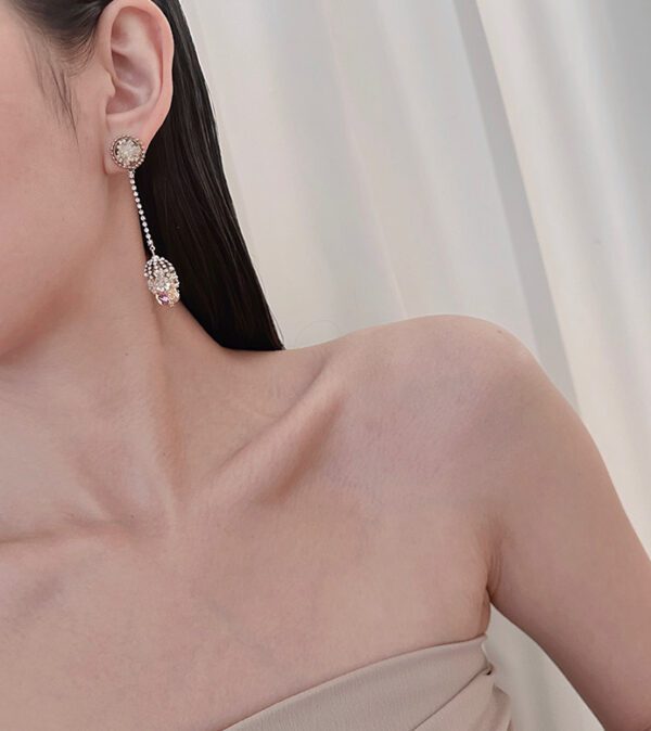 A woman wearing a beige dress and E2018 earrings.