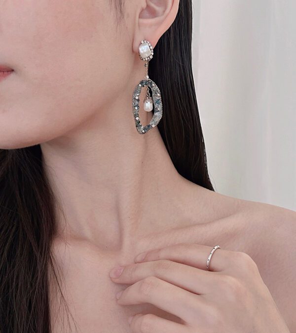 A woman wearing a pair of E2015 earrings and a ring.