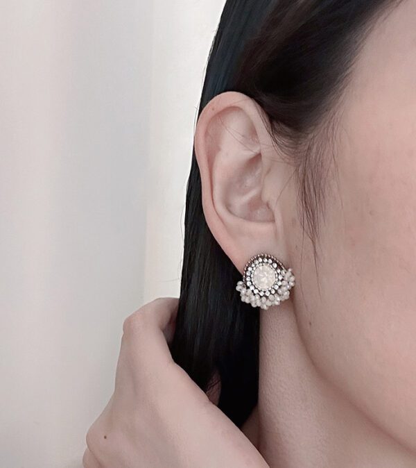 A woman wearing a pair of E933 (Opal White) earrings.