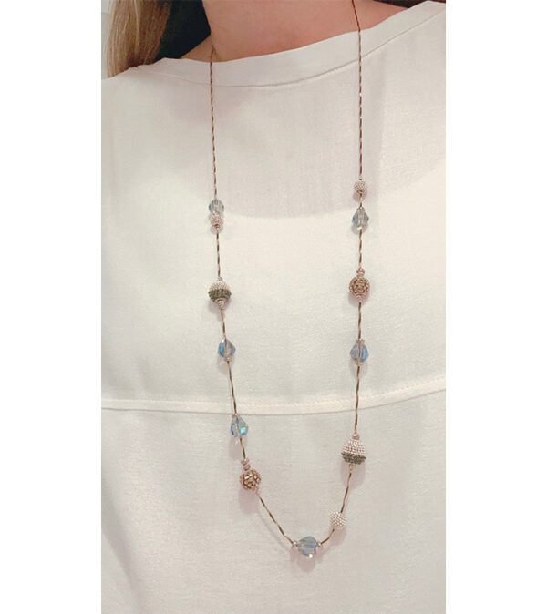 A woman is wearing the NK2072(Smokey) necklace with blue and white beads.