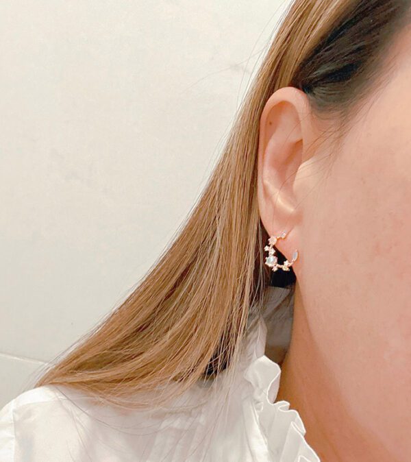 A woman wearing a white shirt and E0739 shaped earrings.