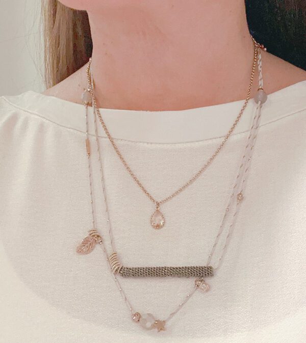 A woman wearing the NK0707 necklace with several charms on it.