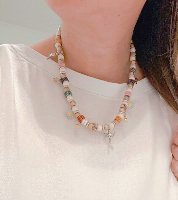 A woman wearing necklace NK128 with beads and charms.