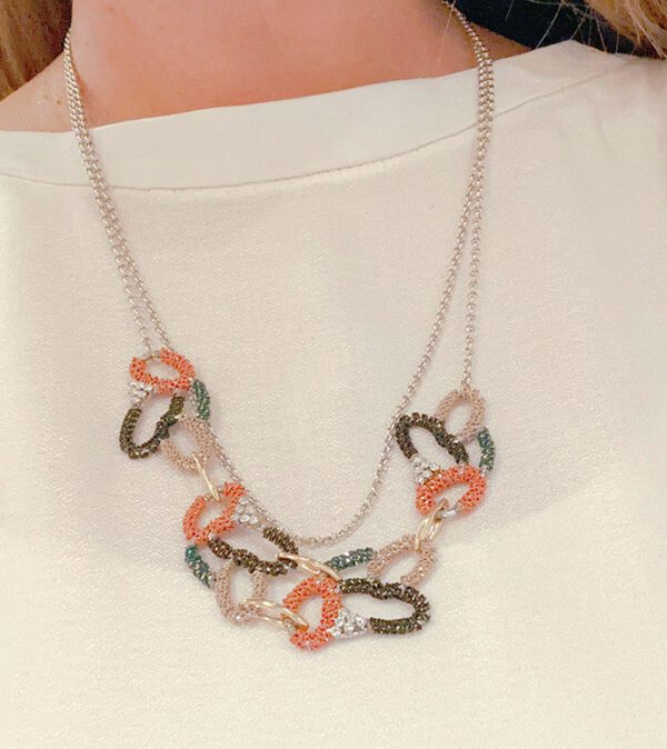 A woman is wearing necklace NK090 with multi colored chains.