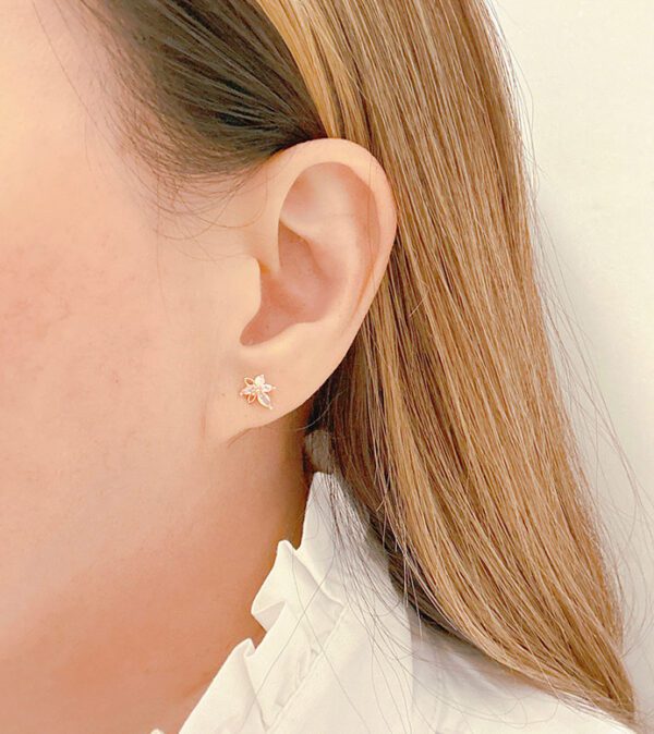 A woman wearing a white blouse and E0725 ear studs.