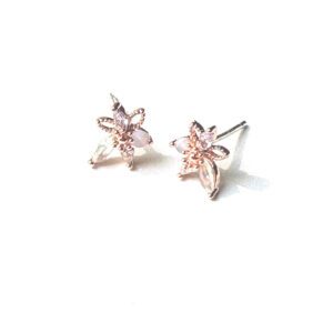 A pair of E0725 stud earrings with pink flowers on a white surface.