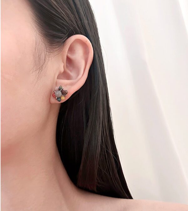 A woman wearing a pair of E672 earrings with a flower on them.