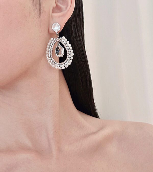 A woman wearing a pair of E726101 earrings with pearls and diamonds.