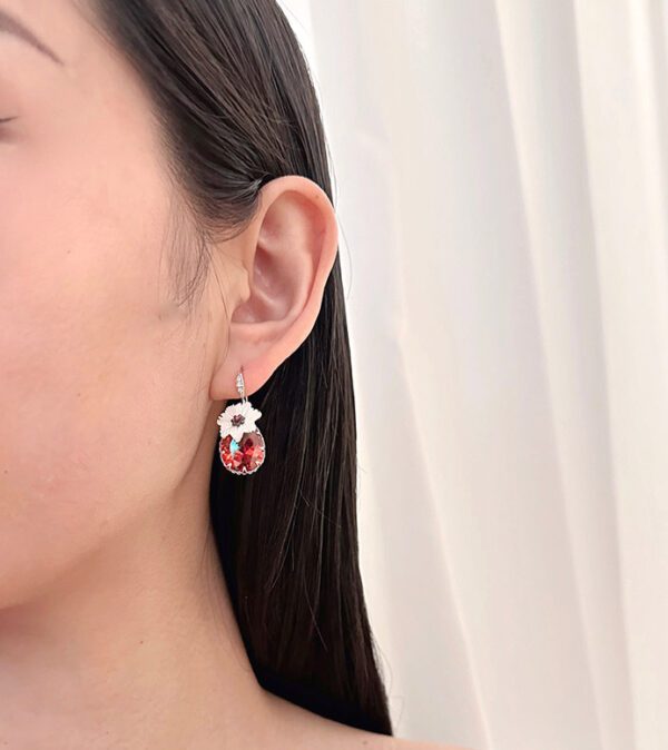 A woman wearing a pair of E00609 (Ruby) earrings.