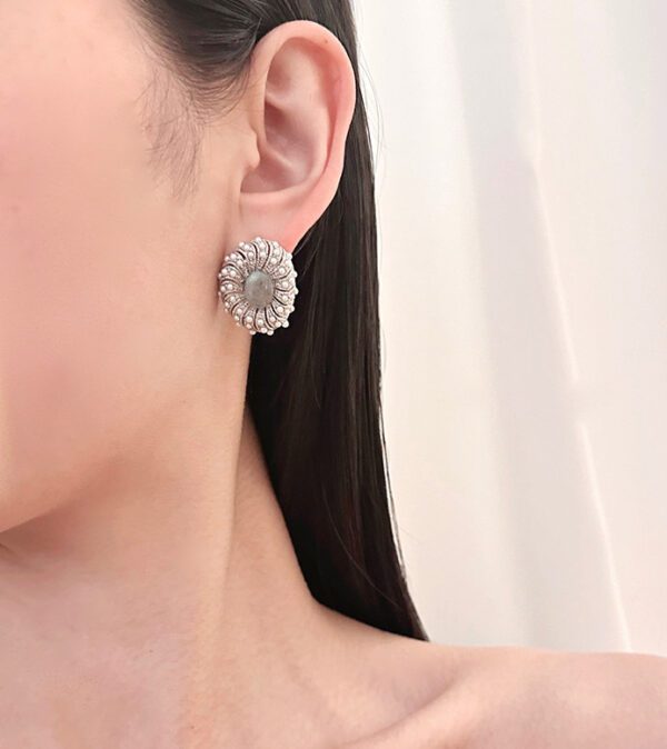 A woman wearing a pair of E102634 (Silver) earrings with a flower on them.