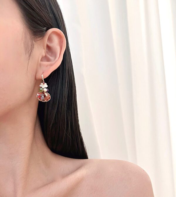 A woman wearing a pair of E00409 (Ruby) earrings.