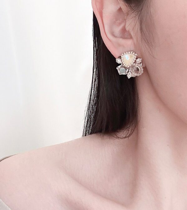 A woman wearing a pair of E24817 (Light) earrings with flowers on them.