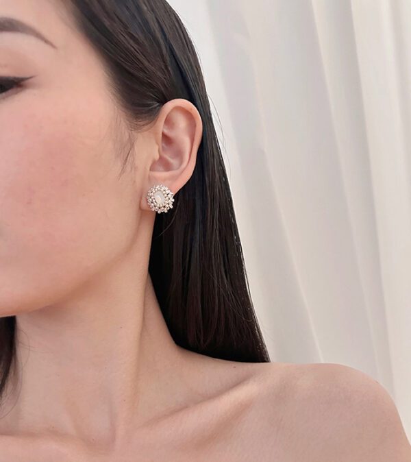 A woman wearing the E24812 (White) top and a pair of earrings.