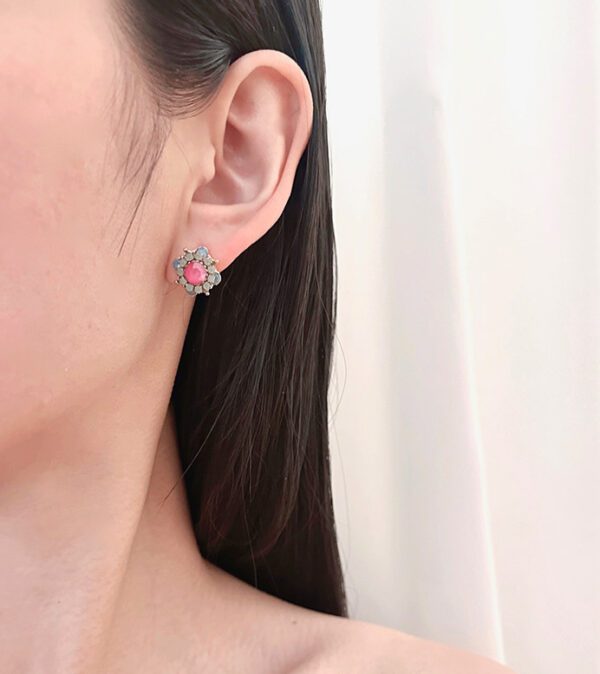 A woman's ear with a E117 (Pink) earring.