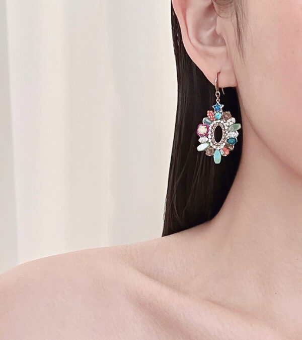 A woman wearing a pair of E24811 (Multi) earrings with multi colored stones.