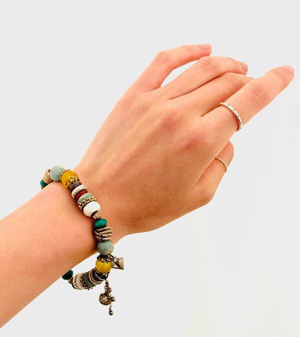 A woman's hand holding a B5918 bracelet with beads and a ring.