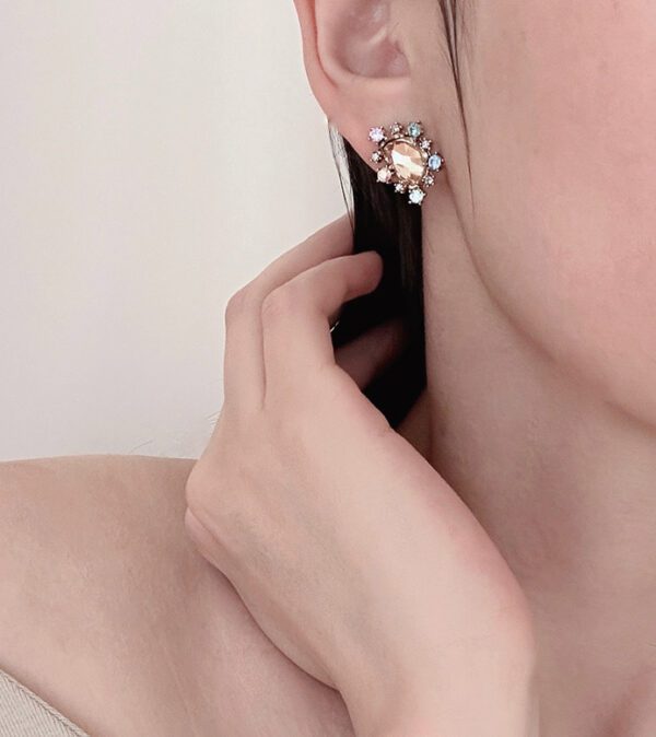 A woman wearing a pair of E9126 earrings with crystals on them.