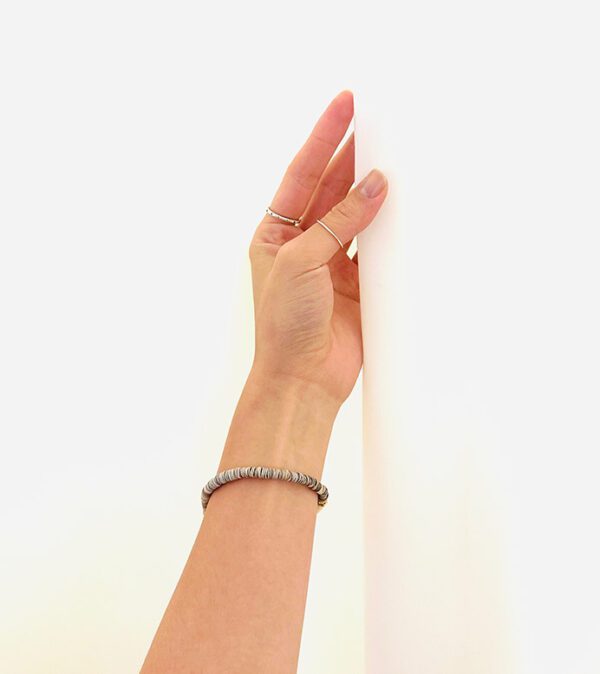 A woman's hand reaching up to a B3203 wall.