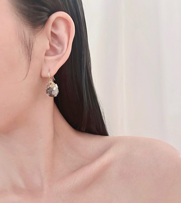 A woman wearing a pair of E8826 earrings with a stone in the middle.