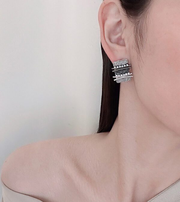 A woman wearing a pair of E8619 (Silver Black) earrings.