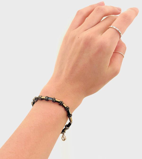 A woman's hand holding a black B1010 bracelet.