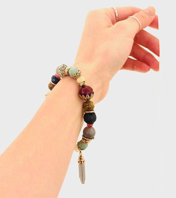 A woman's hand holding a B0508 with beads and tassels.