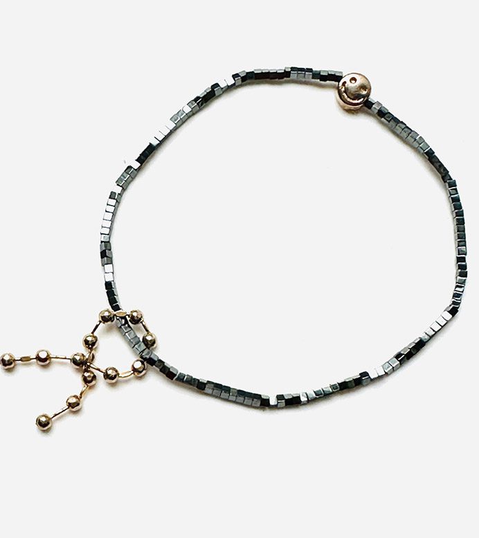B208, a black beaded bracelet with a gold charm.
