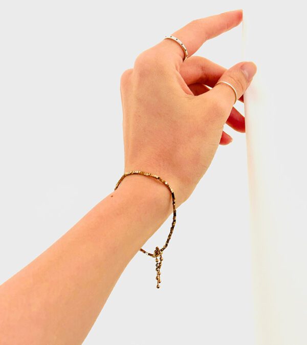 A woman's hand is holding a B208 bracelet.