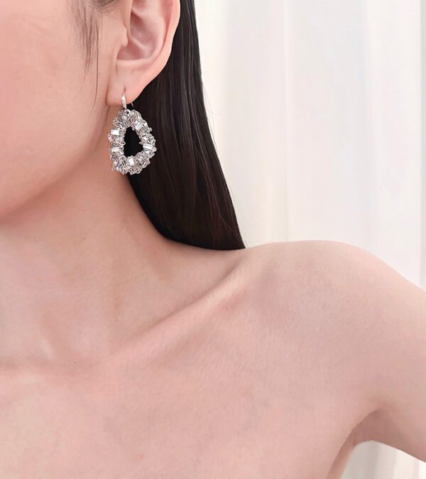 A woman wearing a white top and a pair of E5011 earrings.