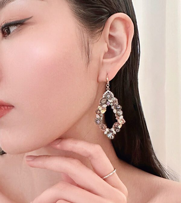 A woman wearing a pair of E5002 earrings with crystals on them.