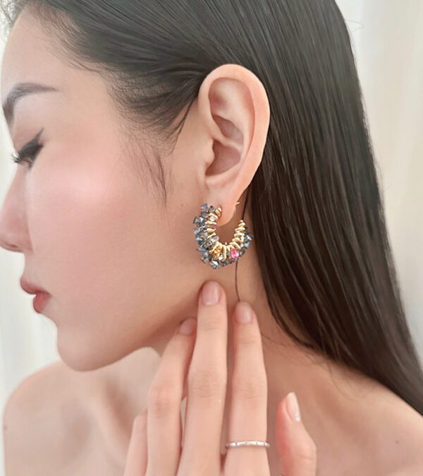 A woman wearing a pair of E4139 earrings and a ring.