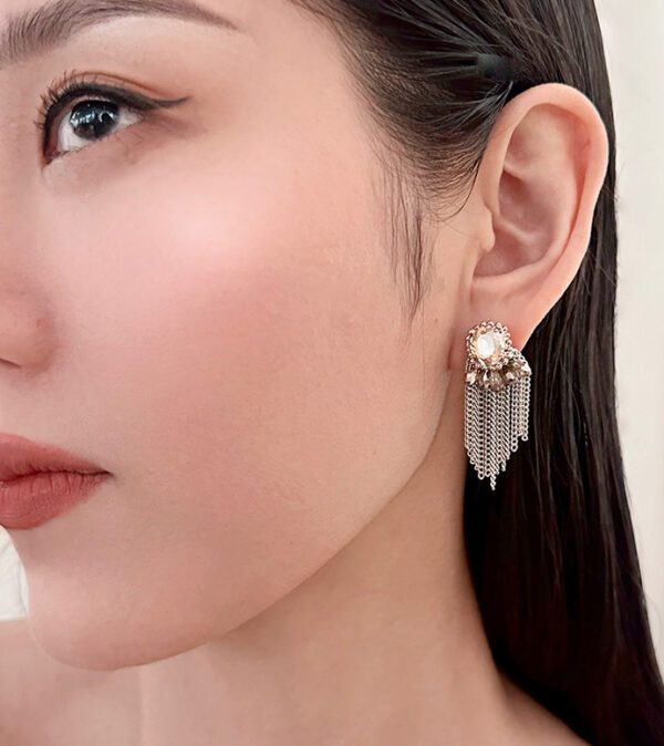 A woman wearing a pair of E4106 earrings with tassels.