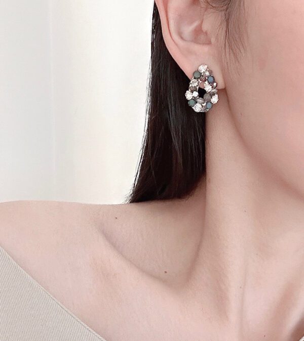 A woman wearing a pair of earrings with E2485 rhinestones.