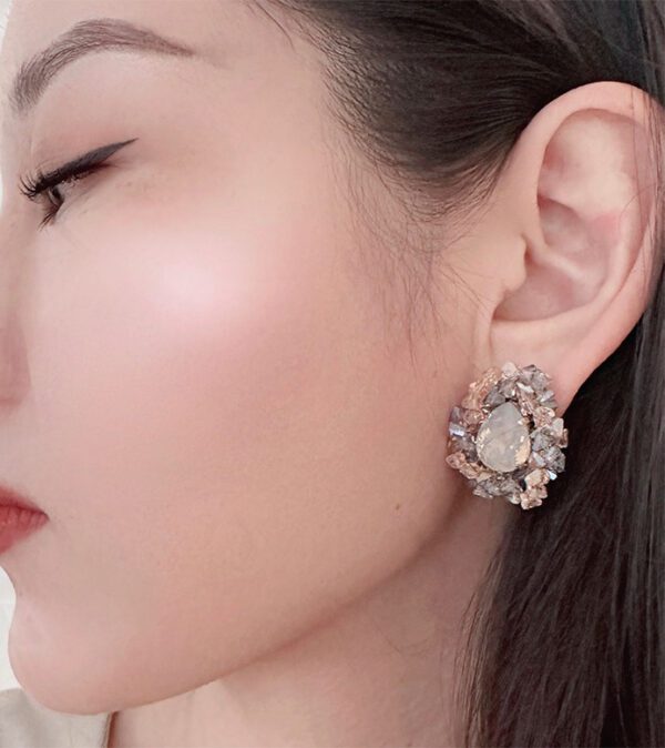 A woman wearing a pair of E2413 earrings with a flower on them.