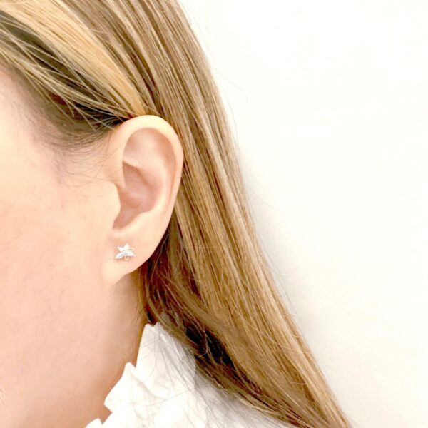 A woman wearing a white blouse and E0700 ear studs.