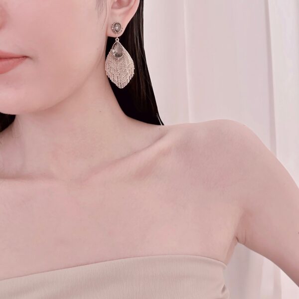 A woman wearing a beige top and a pair of E2517 earrings.