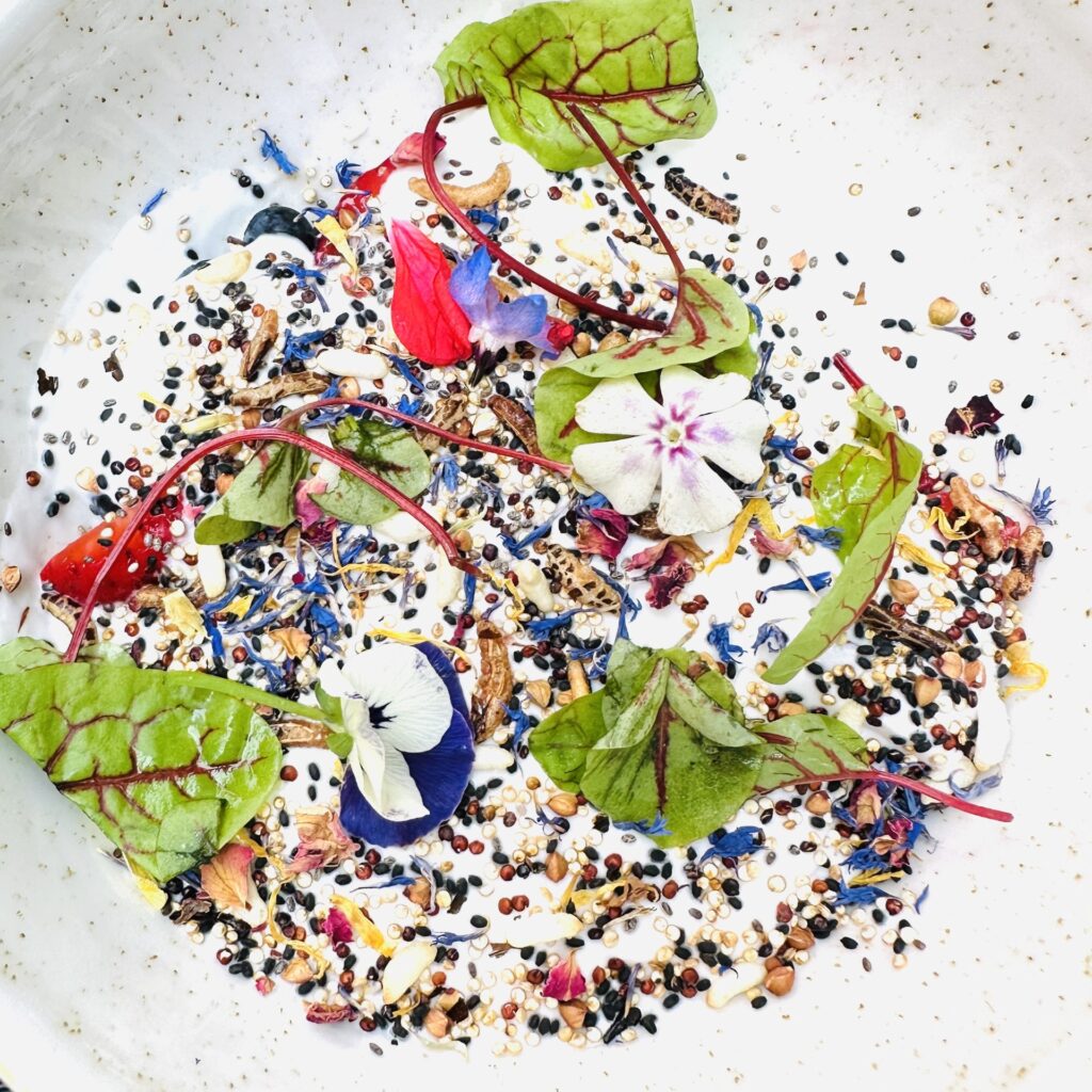 A white bowl with flowers and seeds in it.