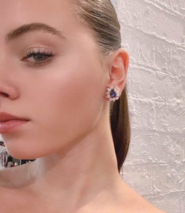 The model is wearing a pair of E2481 (Holiday) earrings with purple stones.